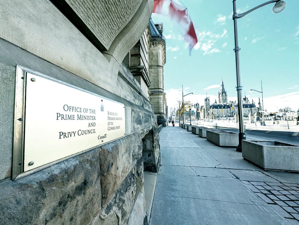 Sign on the front of the Office of the Prime Minister of Canada in Ottawa and view down Wellington Street